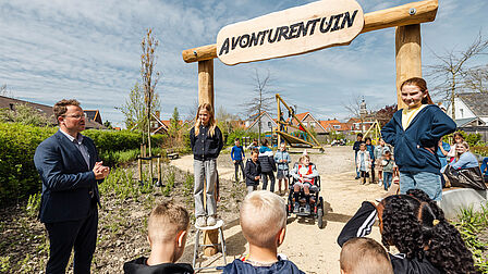 Wethouder met kinderen bij bord Avonturentuin ingang speeltuin