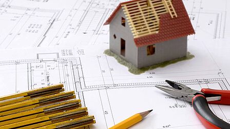 bouwplan met huis en potloden