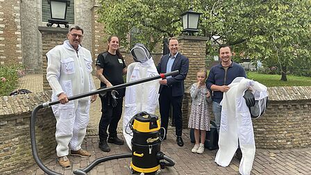 Wethouder Van Leeuwen (midden) overhandigd set aan vrijwilligers